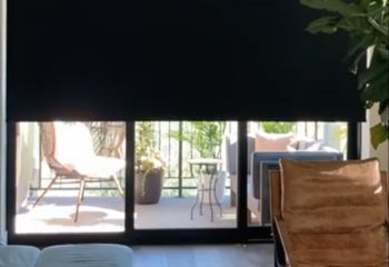 Somfy motorized blackout shades fully closed on large glass balcony doors in a Thousand Oaks living room, providing complete privacy and light blocking.